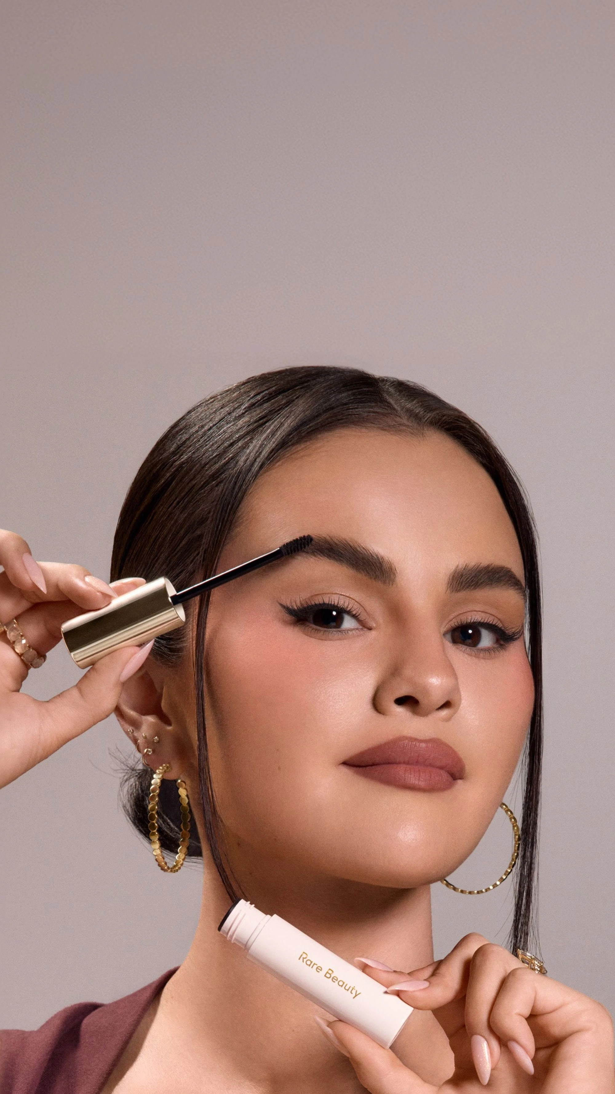 Selena Gomez holding the Jumbo Brow Harmony Flexible Lifting Gel next to her face