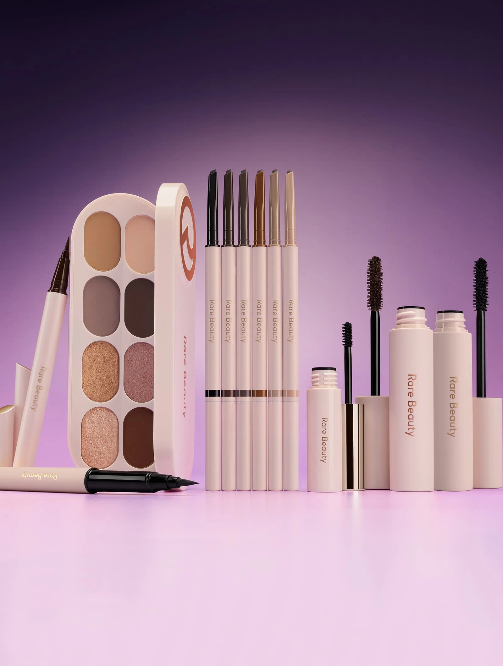 Rare Beauty eye products lined up on a lilac backdrop