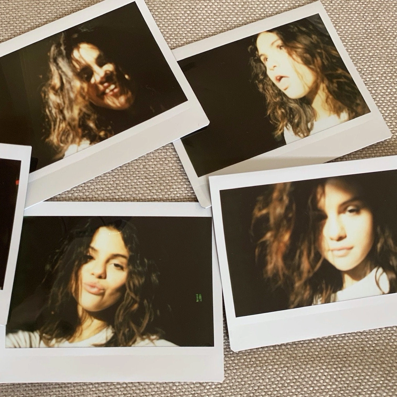 Instant photo prints of Selena Gomez laid out on a table