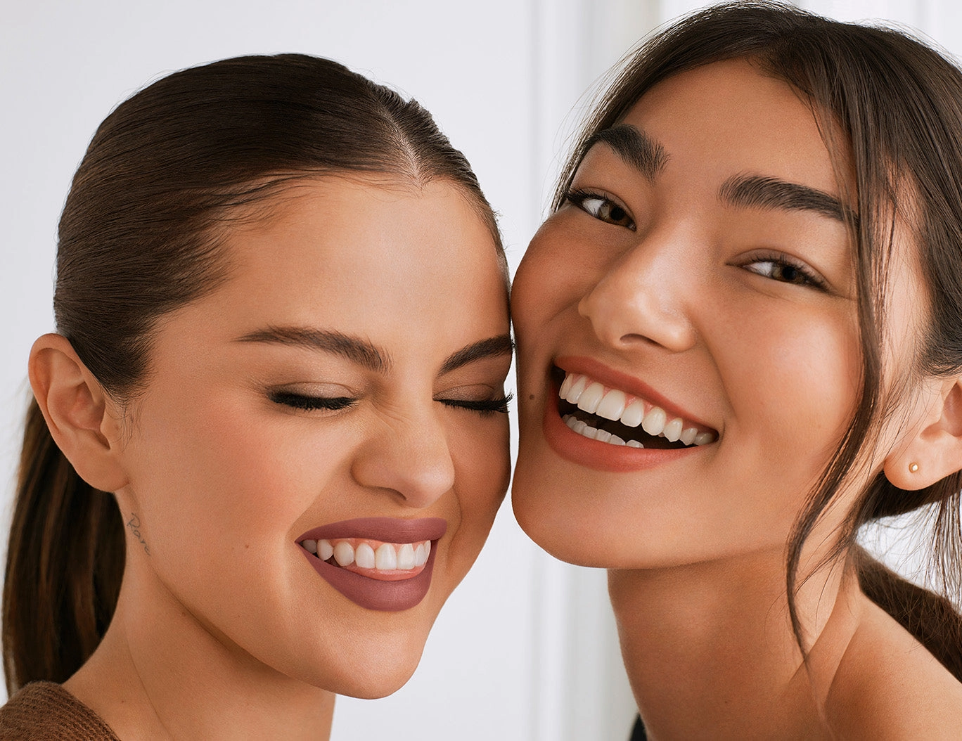Two friends laughing together, cheek to cheek