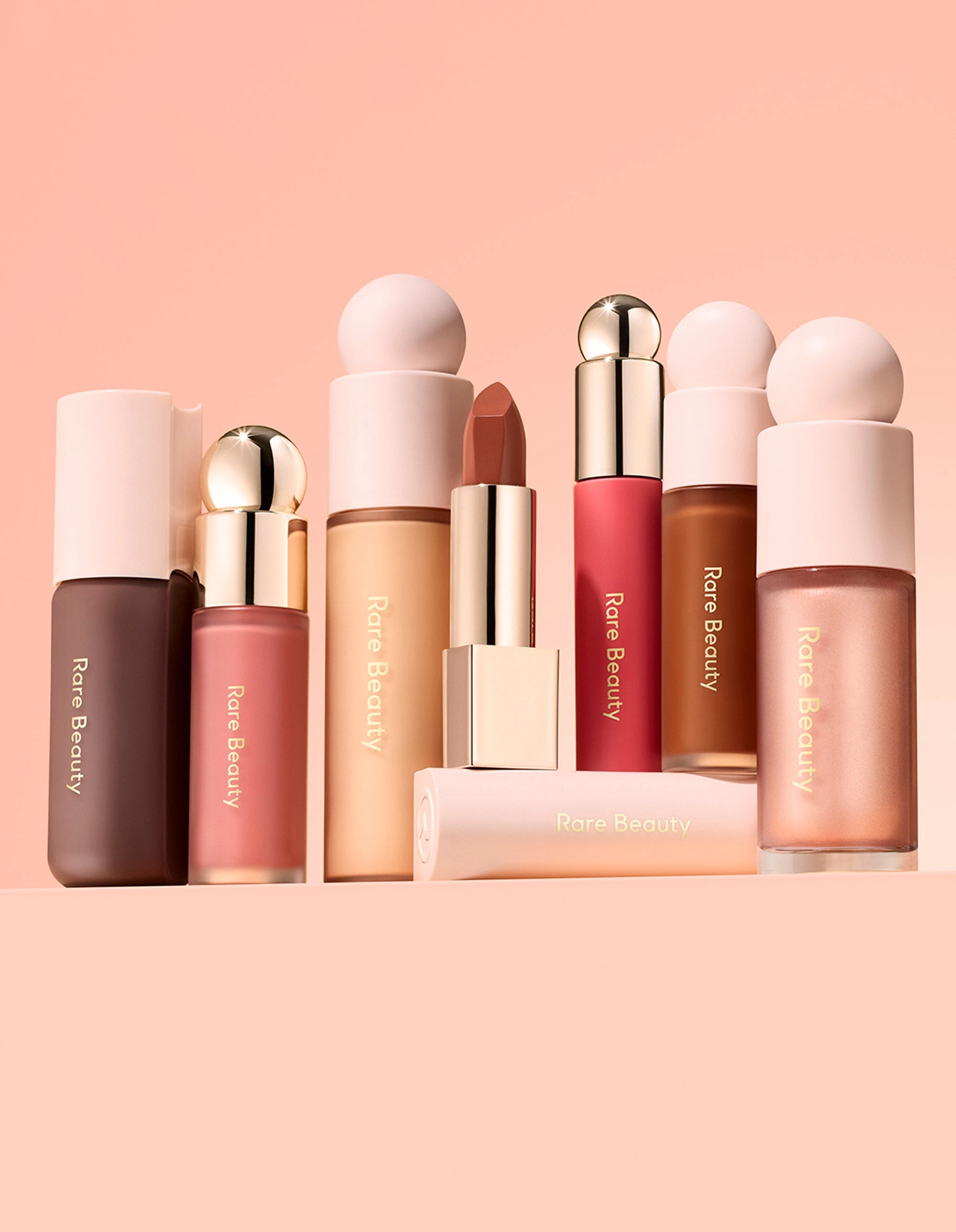 The Rare Beauty accessible collection arranged on a pink backdrop